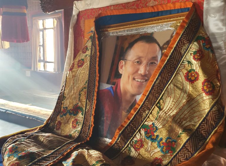 Fotografie představeného kláštera ho "zastupuje" v době, kdy cestuje a společných rituálů se neúčastní. Khenpo Tenpa Yungdrung tráví obvykle několik měsíců v roce v Evropě, kde učí západní zájemce o buddhismus. Loni ani letos zatím ještě ale z kláštera nevycestoval.